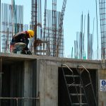 man kneeling on unfinished building during daytime
